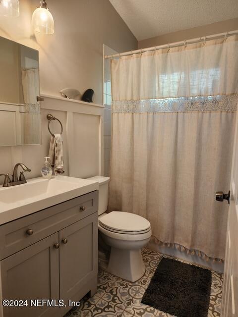 bathroom featuring walk in shower, vanity, a textured ceiling, tile patterned flooring, and toilet