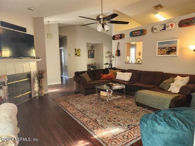 living room with dark hardwood / wood-style floors, ceiling fan, lofted ceiling, and a tile fireplace