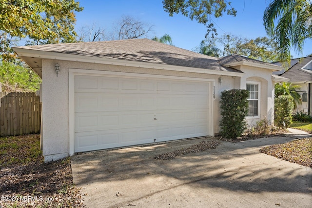 view of front of house with stucco siding, an attached garage, concrete driveway, and fence