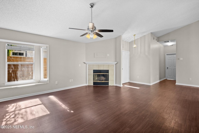 unfurnished living room with a textured ceiling, wood finished floors, ceiling fan, vaulted ceiling, and a tile fireplace