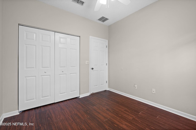 unfurnished bedroom with dark wood finished floors, baseboards, visible vents, and a closet