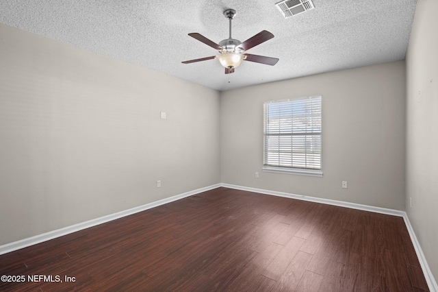 spare room featuring a ceiling fan, baseboards, visible vents, dark wood finished floors, and a textured ceiling