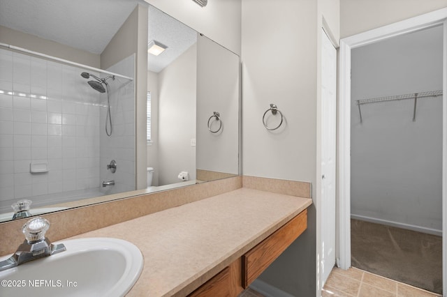 full bathroom featuring vanity, tile patterned flooring, tiled shower / bath combo, toilet, and a textured ceiling