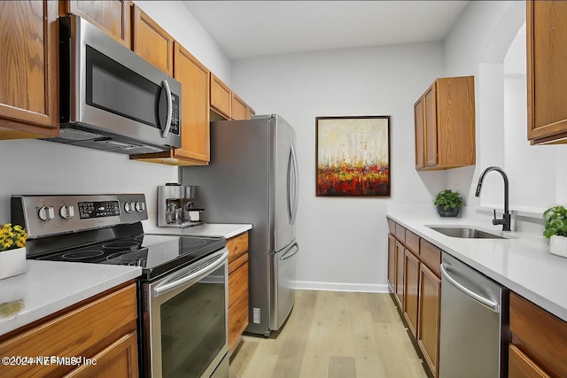 kitchen with appliances with stainless steel finishes, light wood-type flooring, and sink