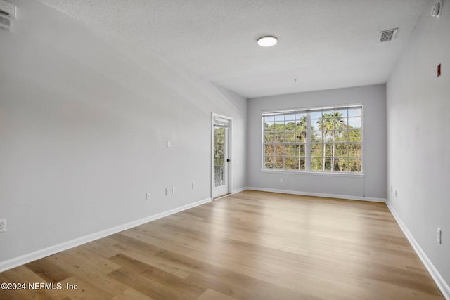 unfurnished room with light hardwood / wood-style flooring and a textured ceiling