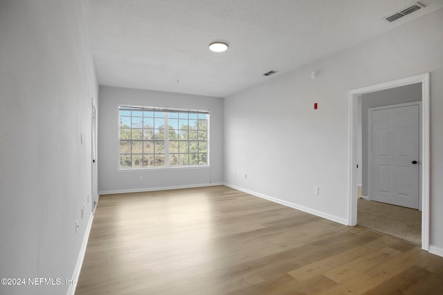 spare room featuring light hardwood / wood-style flooring and a textured ceiling