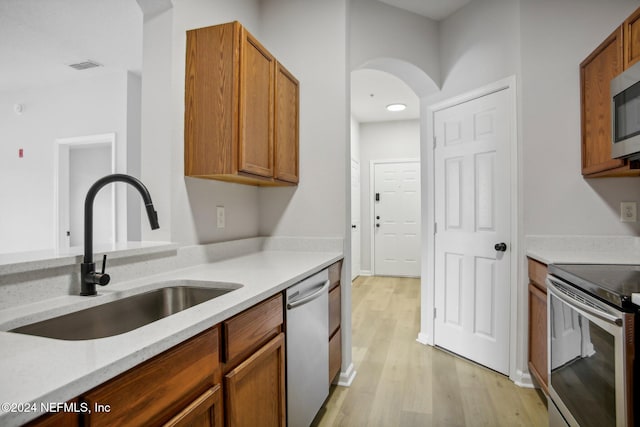 kitchen with sink, stainless steel appliances, and light hardwood / wood-style flooring