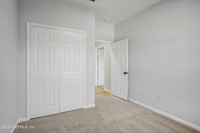 unfurnished bedroom featuring light carpet and a closet