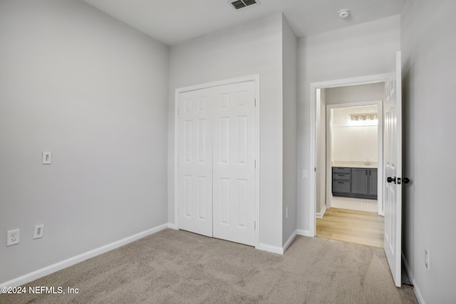 unfurnished bedroom featuring light colored carpet and a closet