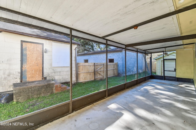 unfurnished sunroom featuring beam ceiling and plenty of natural light