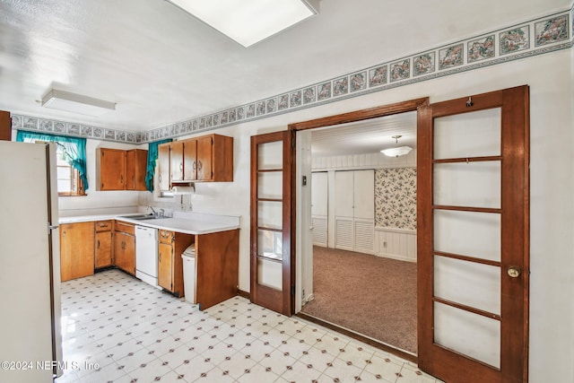 kitchen featuring sink, light colored carpet, and white appliances