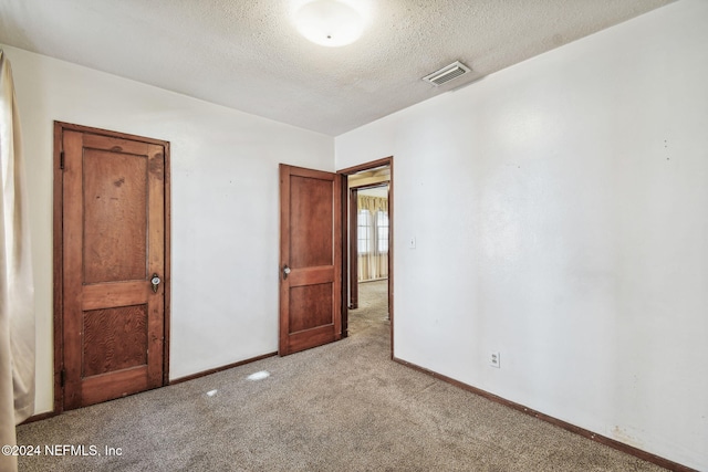 spare room featuring a textured ceiling and light carpet