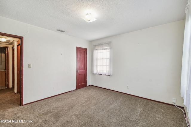 empty room with a textured ceiling and carpet floors