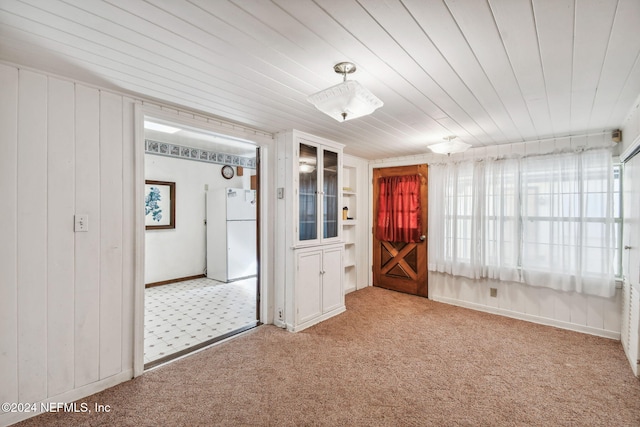 spare room with wooden ceiling, light carpet, and wooden walls