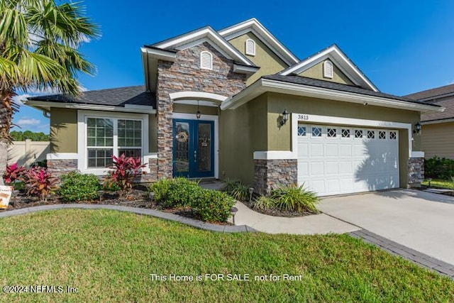 craftsman house with french doors, a front yard, and a garage