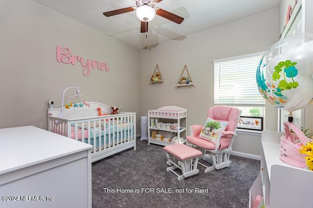 carpeted bedroom featuring a nursery area and ceiling fan