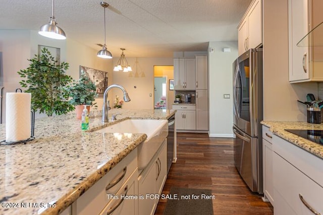 kitchen featuring white cabinets, appliances with stainless steel finishes, decorative light fixtures, and light stone countertops