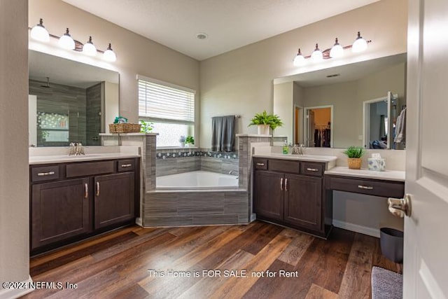 bathroom featuring wood-type flooring, vanity, and tiled bath