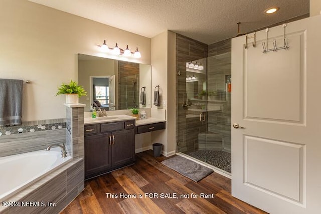 bathroom with vanity, wood-type flooring, a textured ceiling, and shower with separate bathtub