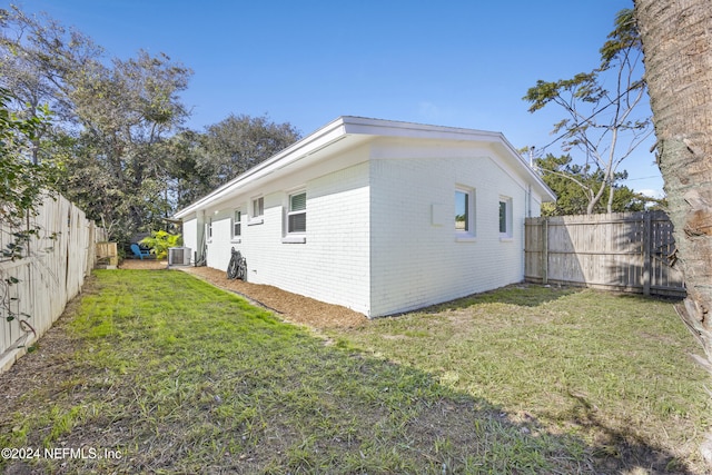 view of side of property featuring a lawn and central air condition unit