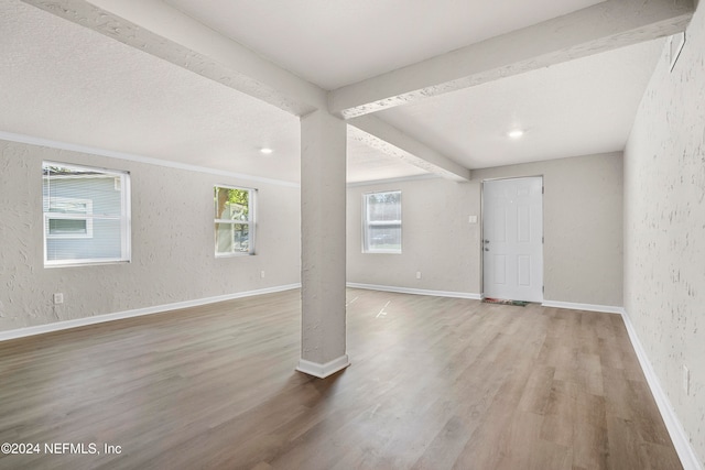 unfurnished living room with beamed ceiling and wood-type flooring