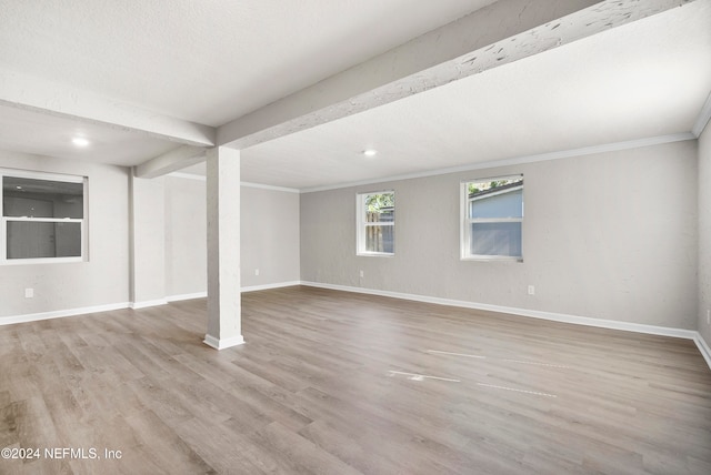 basement with light hardwood / wood-style flooring and ornamental molding