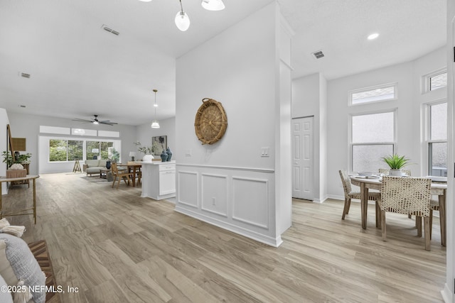 interior space with pendant lighting, light hardwood / wood-style floors, white cabinetry, and ceiling fan