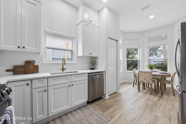 kitchen featuring sink, white cabinets, stainless steel appliances, and light hardwood / wood-style flooring