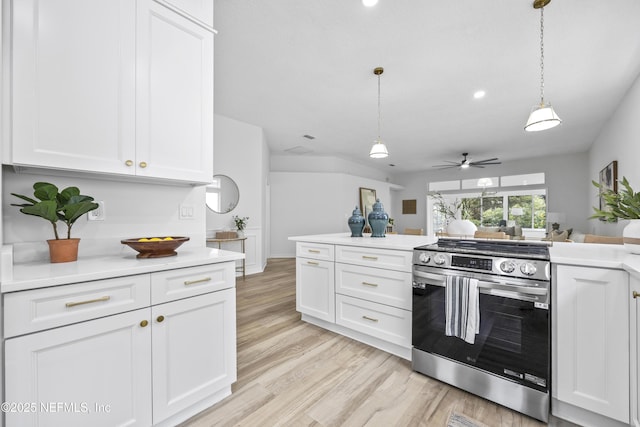 kitchen with stainless steel range, decorative light fixtures, white cabinets, and light hardwood / wood-style flooring