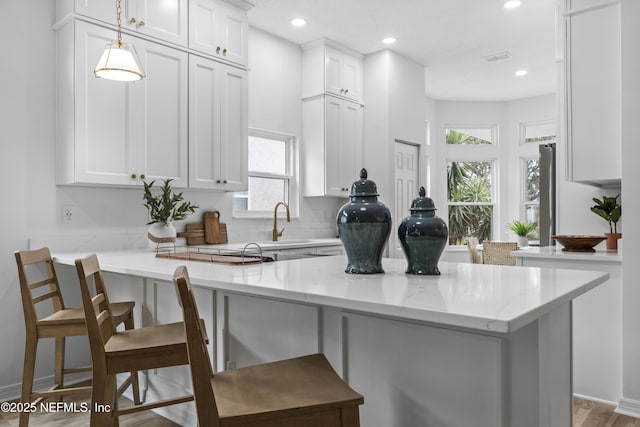 kitchen featuring pendant lighting, a breakfast bar, white cabinets, and kitchen peninsula