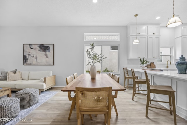 dining room with light wood-type flooring, a textured ceiling, and a wealth of natural light