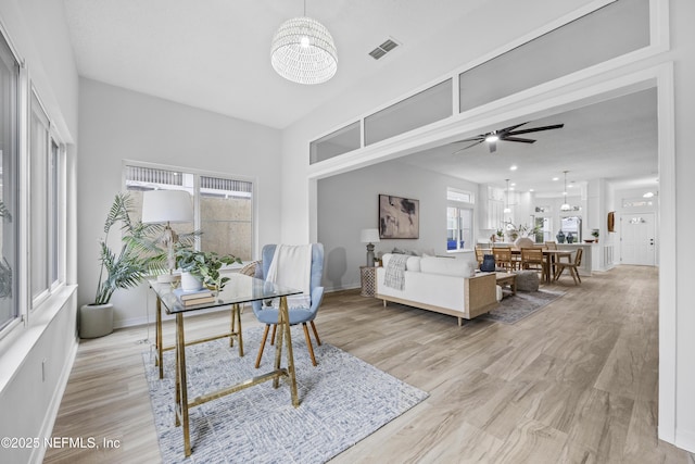 interior space featuring ceiling fan with notable chandelier and light wood-type flooring