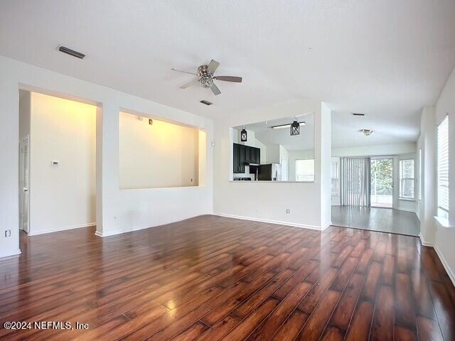 unfurnished living room featuring ceiling fan and dark wood-type flooring