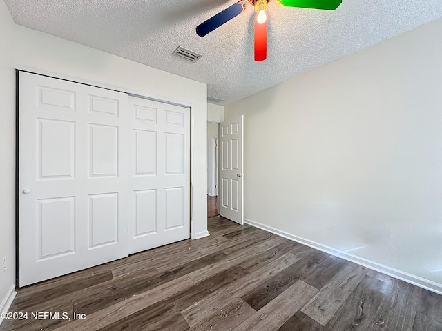 unfurnished bedroom featuring ceiling fan, a textured ceiling, dark hardwood / wood-style flooring, and a closet