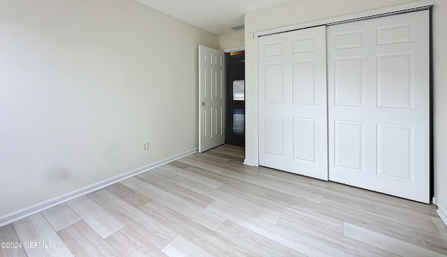 unfurnished bedroom with light hardwood / wood-style flooring and a closet