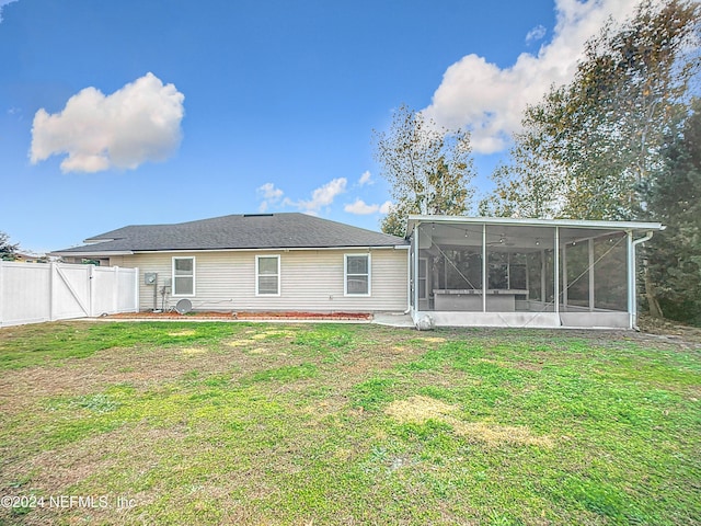 rear view of house featuring a sunroom and a lawn