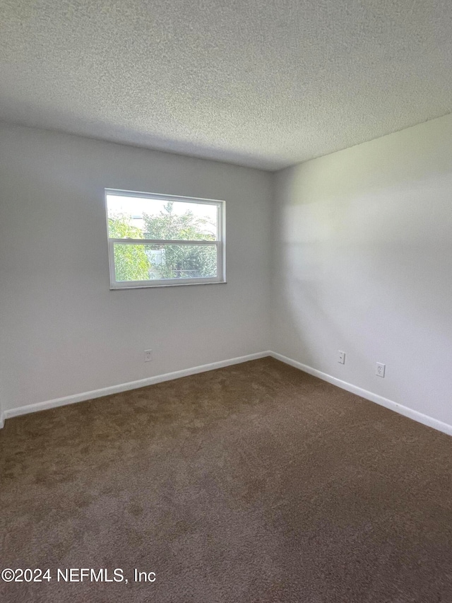 carpeted empty room with a textured ceiling