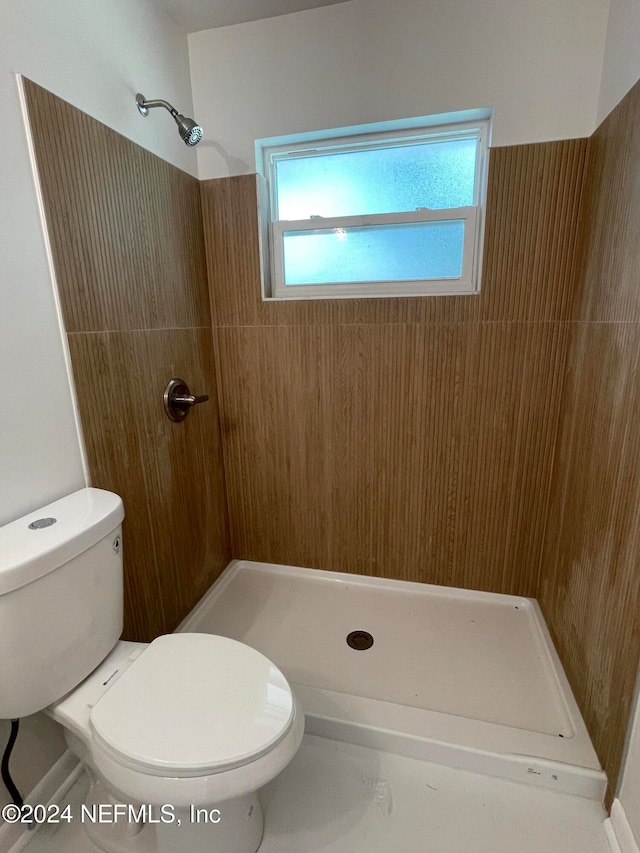 bathroom featuring toilet and a tile shower