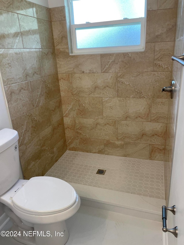 bathroom featuring toilet and a tile shower