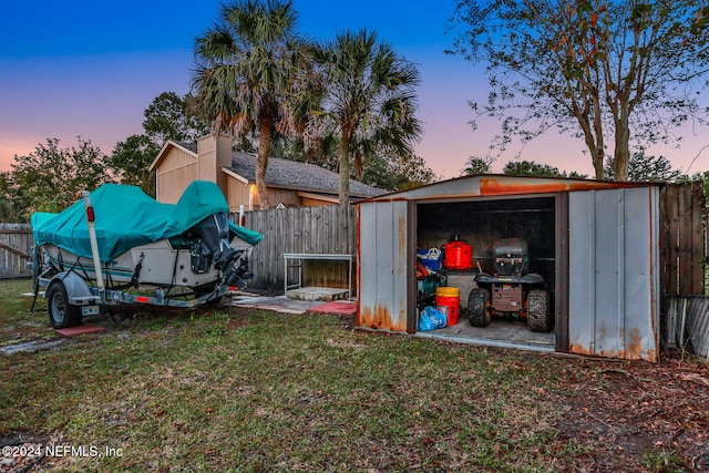 yard at dusk featuring a storage unit