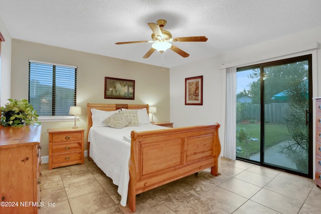 tiled bedroom with access to exterior, a textured ceiling, multiple windows, and ceiling fan