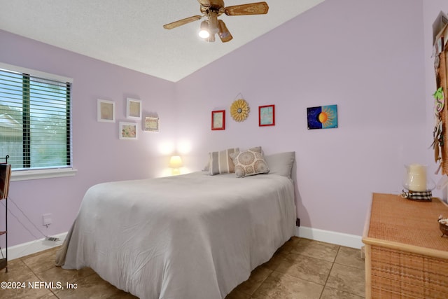 tiled bedroom with ceiling fan and a textured ceiling