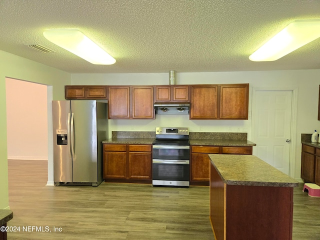 kitchen featuring a textured ceiling, stainless steel appliances, a kitchen island, and dark hardwood / wood-style floors