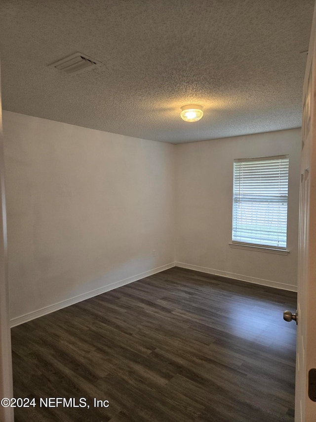 empty room with a textured ceiling and dark hardwood / wood-style floors