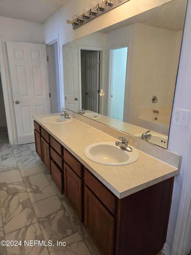 bathroom with vanity, a bathtub, and a textured ceiling