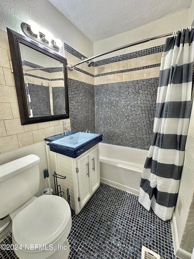 full bathroom featuring vanity, toilet, a textured ceiling, tile walls, and shower / tub combo with curtain