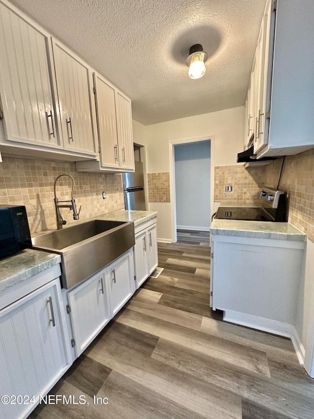 kitchen featuring dark wood finished floors, freestanding refrigerator, a sink, light countertops, and electric stove