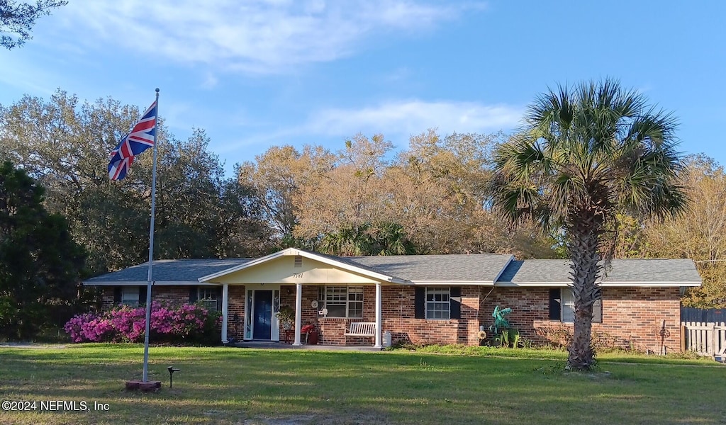 single story home featuring covered porch and a front yard