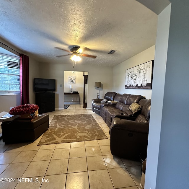 living room with ceiling fan, light tile patterned floors, and a textured ceiling