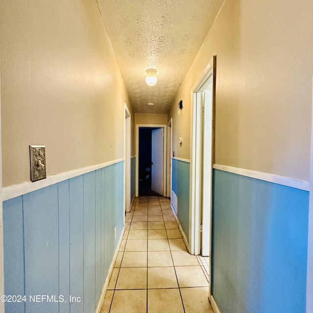 hallway featuring light tile patterned floors and a textured ceiling